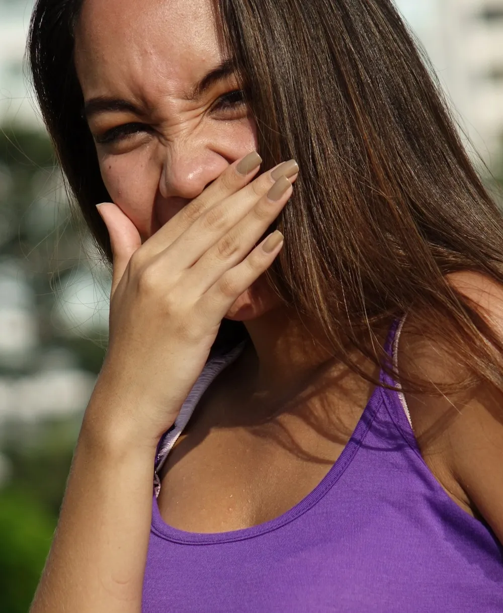 Mulher fazendo careta e cobrindo a boca com a mão