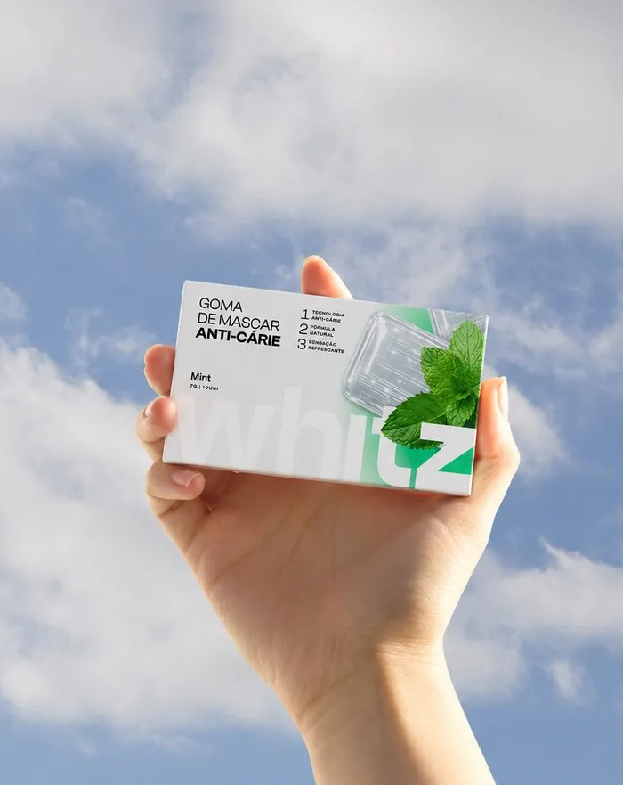 Mão segurando Whitz sabor menta contra o céu